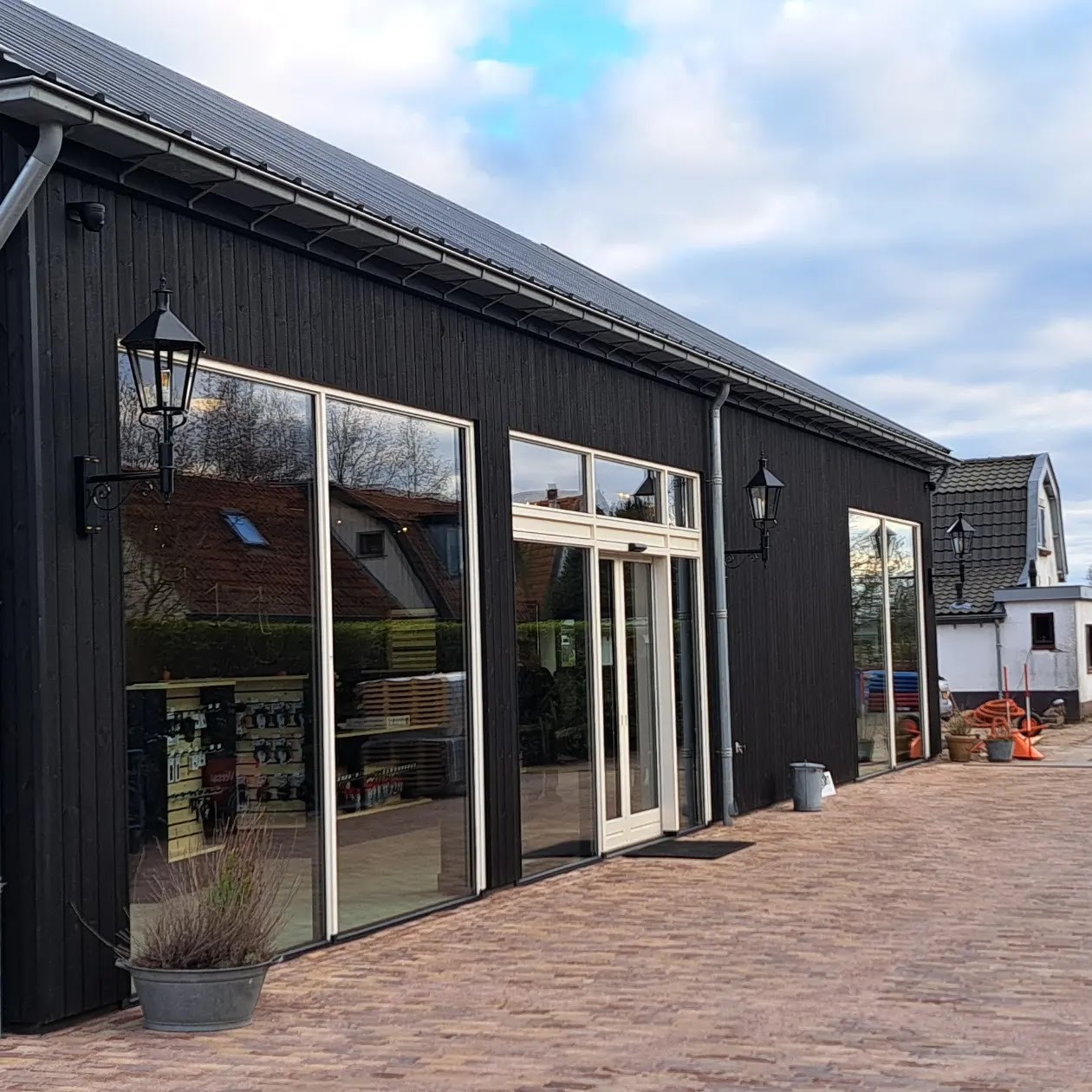 Zwart houten bedrijfspand met hoge glazen gevel en klassieke buitenlantaarns