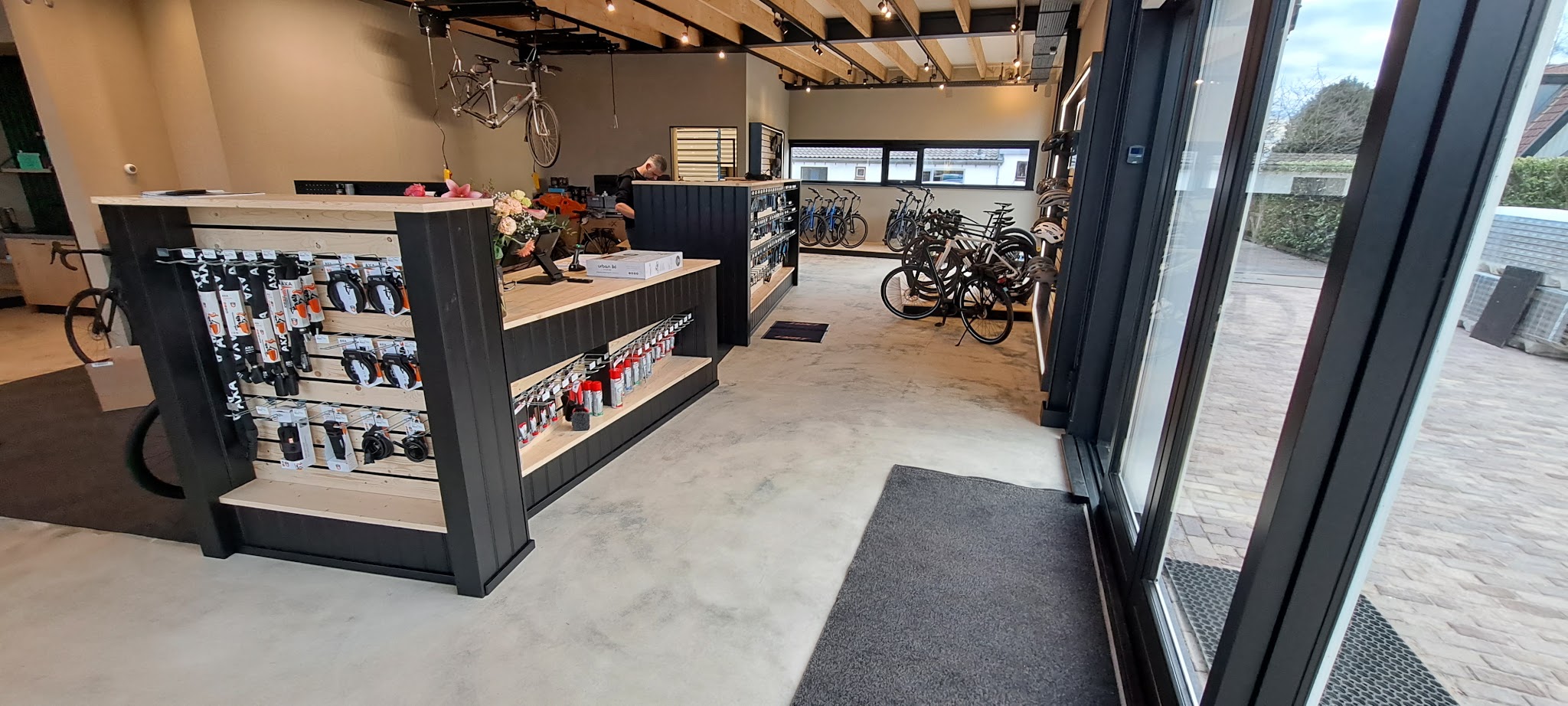 Winkelinterieur met houten balkenplafond, zwarte toonbank met houten blad en gevlinderde betonvloer